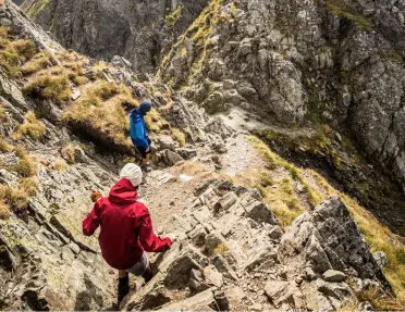 Two people descending a rocky trail on a mountain