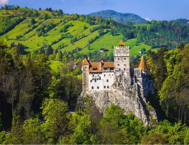 Castle on top of a cliff, surrounded by tall hills and grassy fields