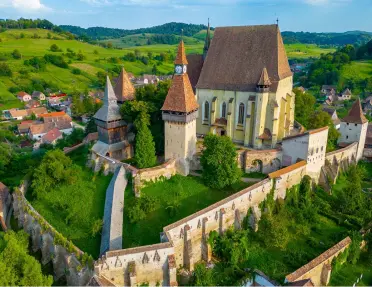 Exterior view of castle-like building with large grass fields and trees