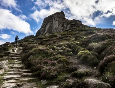 Person ascending rock stairs on the slope of a mountain