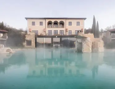 Exterior view of a large, beige building with a foggy outdoor pool in front