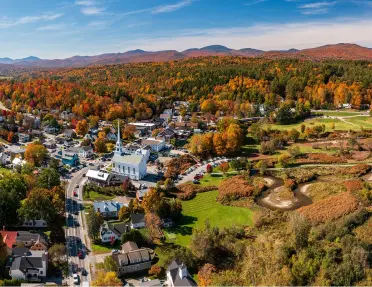Aerial view of the town of Stowe, Vermont, with its iconic white church steeple and fall foliage.