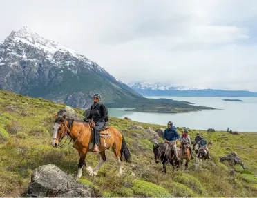 Group of people horseback riding with a large lake in the distance