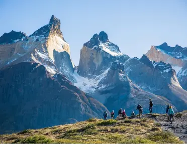 Large mountains with a group of people walking on a smaller mountain