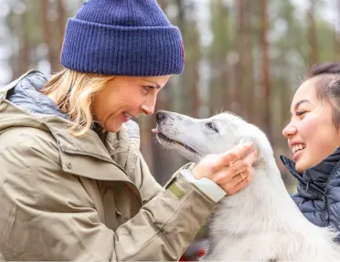 A woman in a blue beanie face to face with a white dog