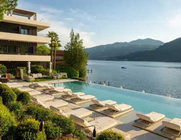 A hotel pool with many lounge chairs overlooks lake Como in Italy.