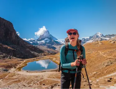 Woman smiling while walking in an open valley, with a lake in the background