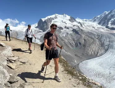 Group of people descending a gravel trail with mountains in the background