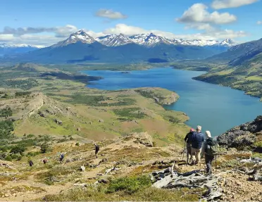 Group of people descending a gravel trail, with views of a valley and large lake