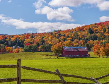 A vibrant red barn set against fall foliage in Vermont