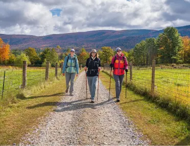 Three women on a hike surrounded by fall foliage on the Vermont Women's Hiking & Walking Tour.