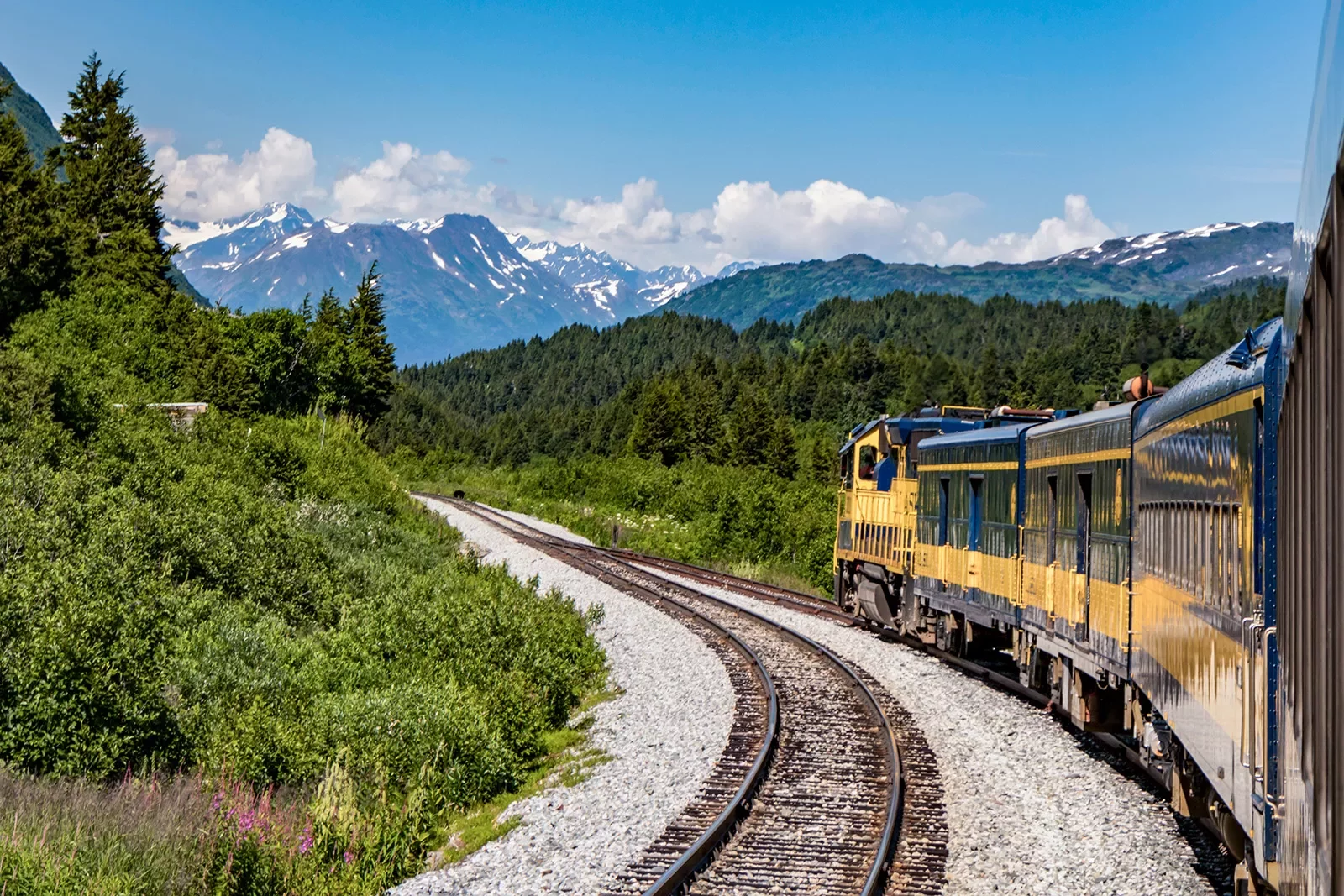 Yellow train with mountains in the background in Alaska
