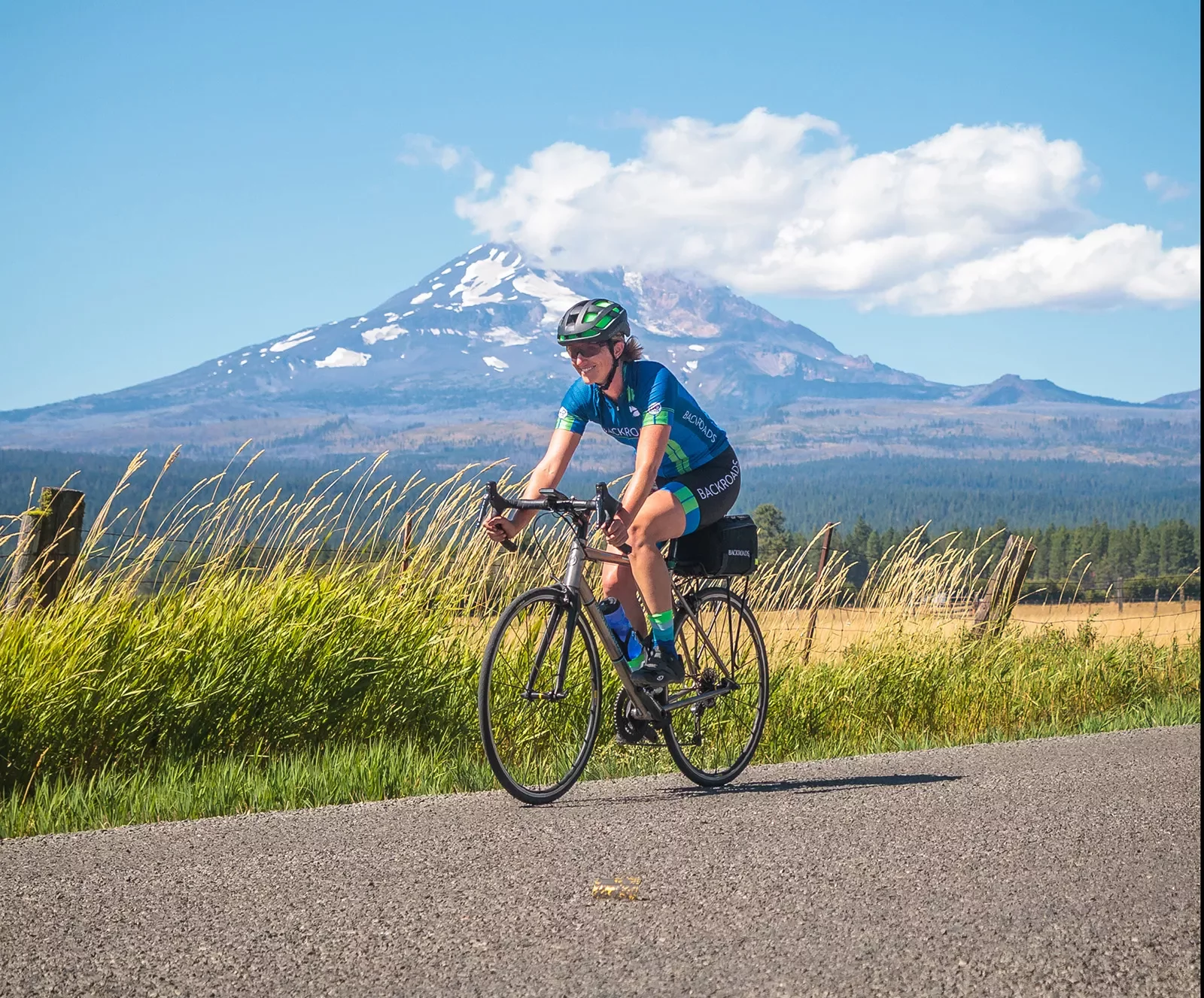 Guest cycling down grassy road, Mount Hood in background.
