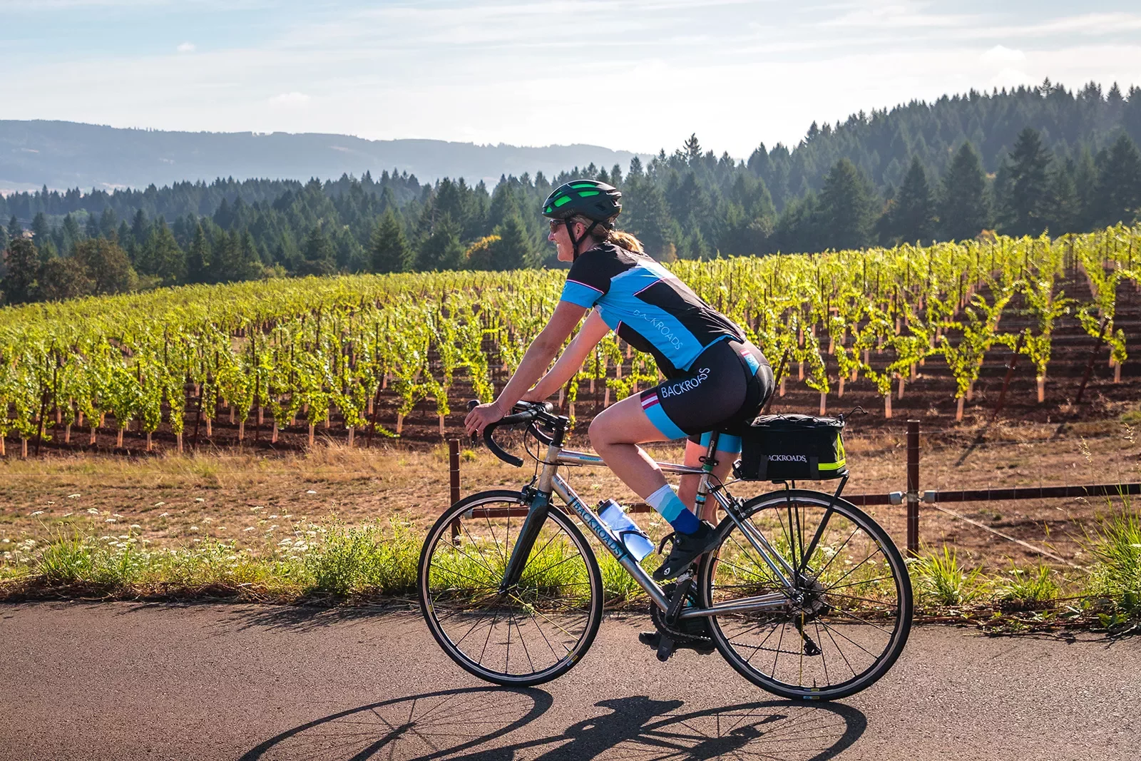 Guest cycling past young vineyard.