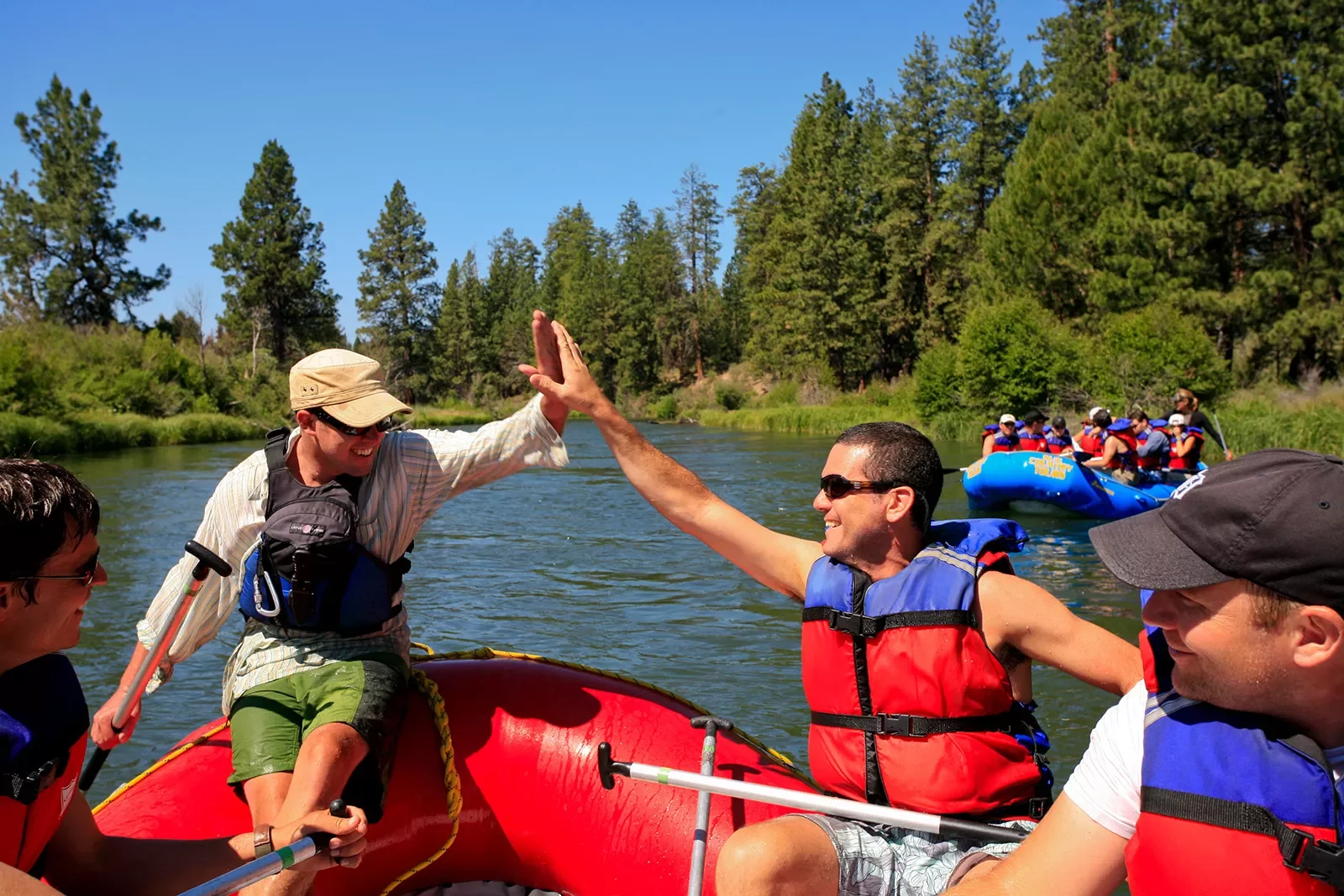 Two guests hi-fiving on rafts.