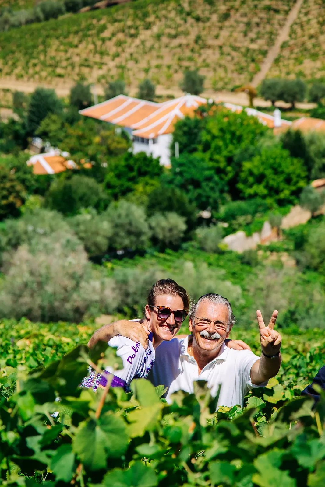 Two people posing in a vineyard.