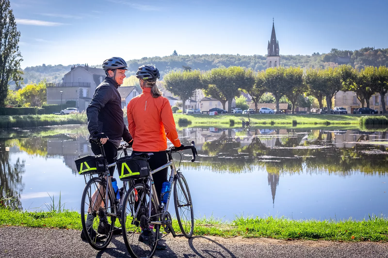 Two guests with bikes looking out towards river, town, hills, church spire.