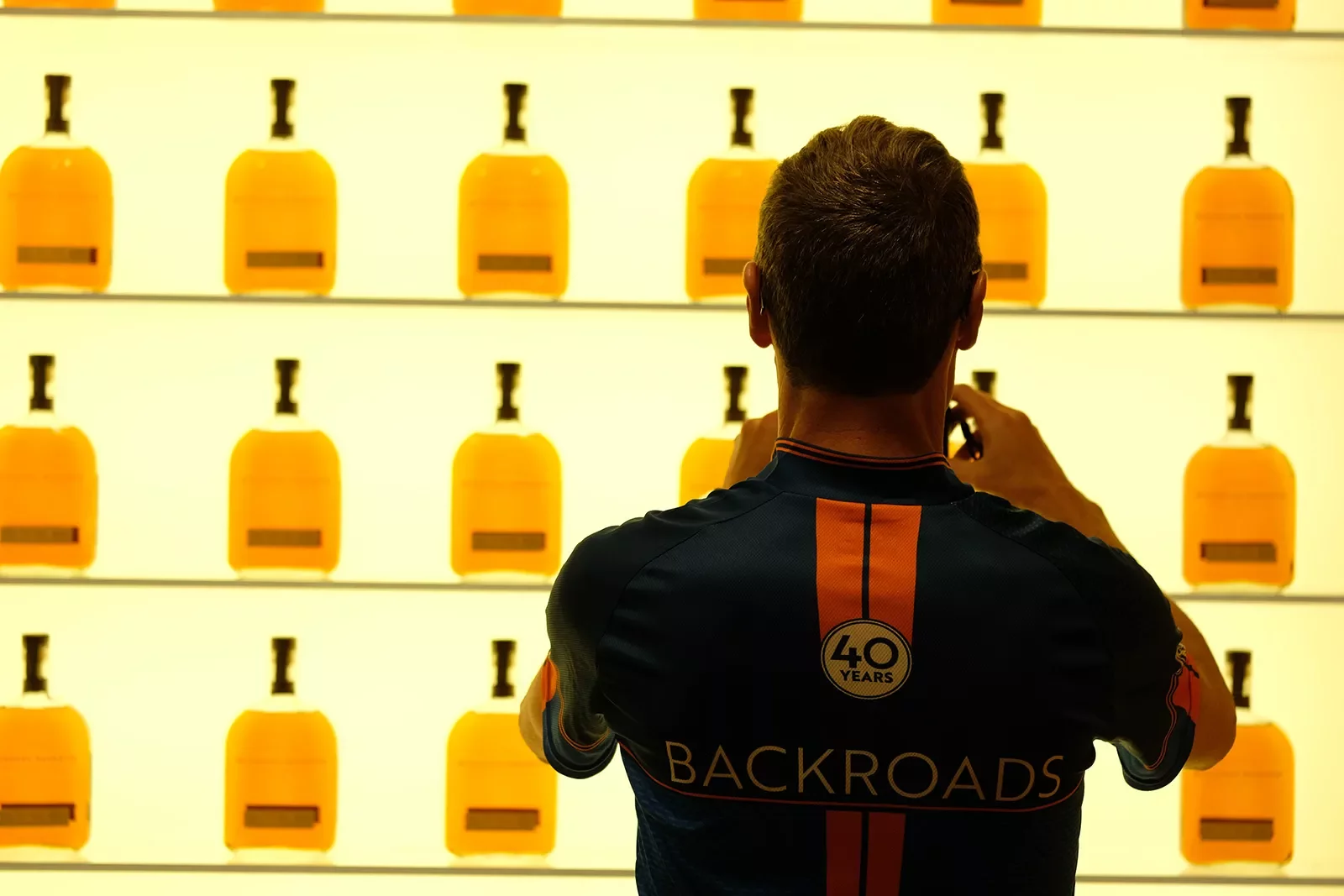 Guest taking photo of wall of whiskey bottles.