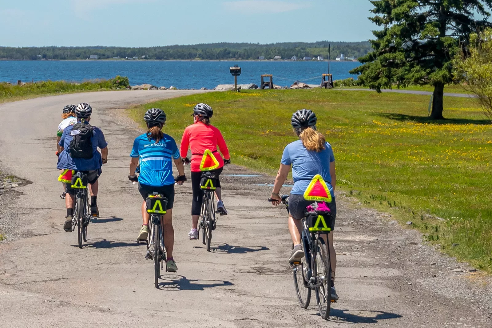Five guests riding along a coastal trail, ocean to their left.