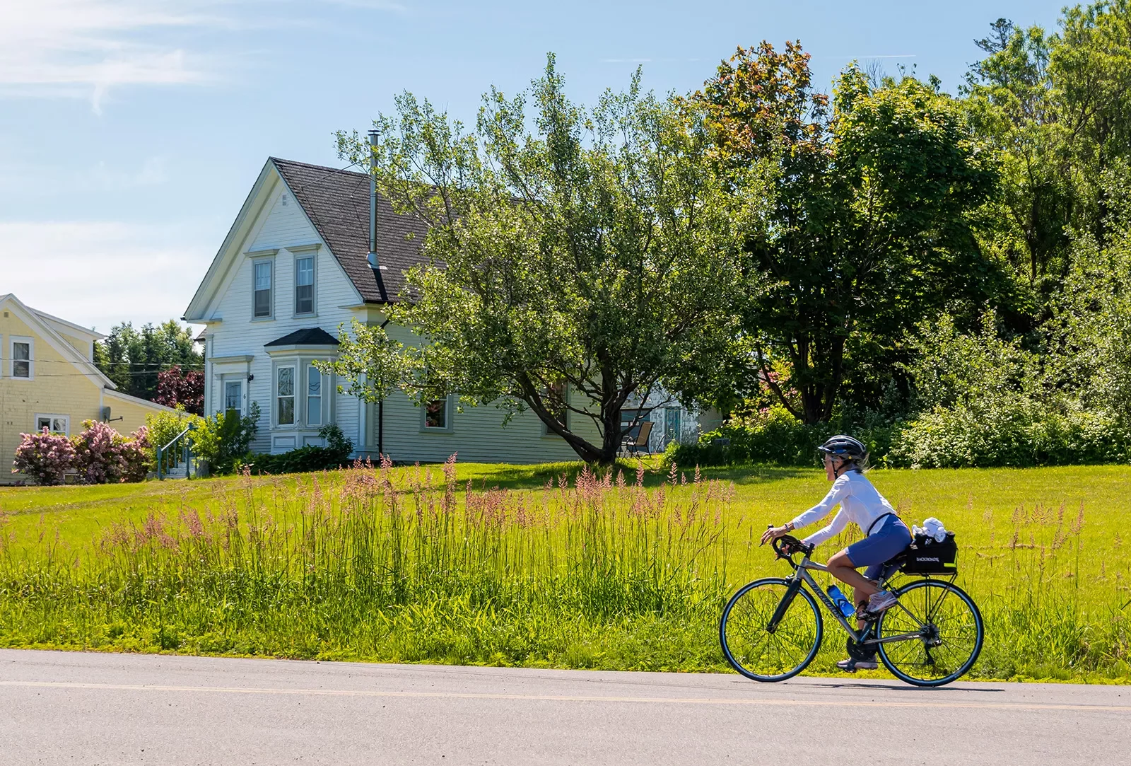 Guest cycling in front of farmhouse and field.
