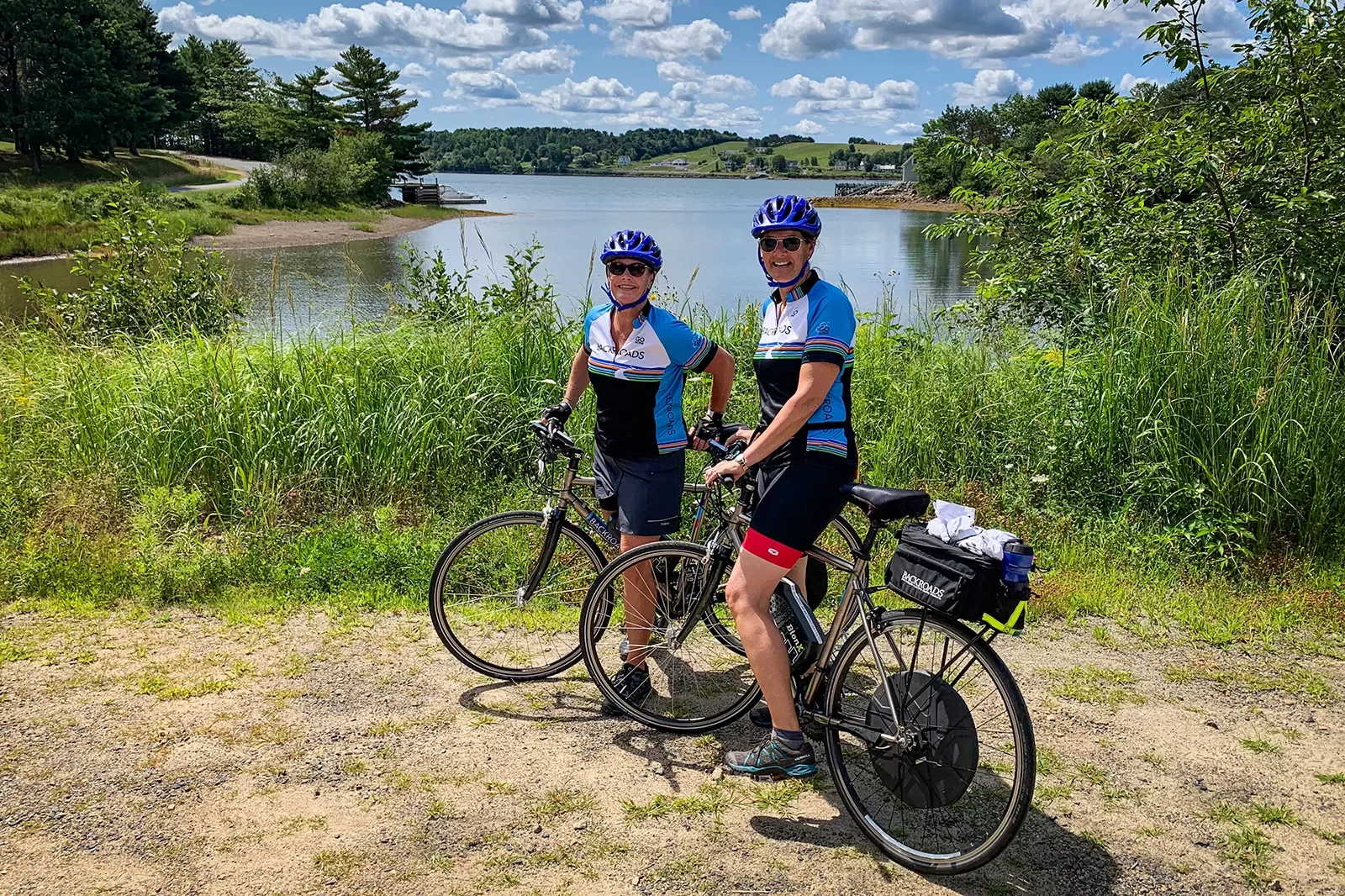 Two guests on their bikes posing in front of small lake.