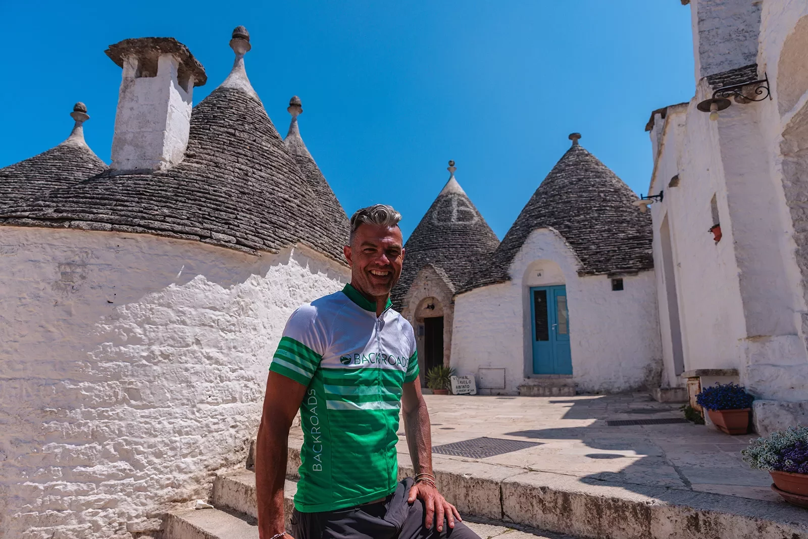 Guest smiling in front of Alberobello houses.