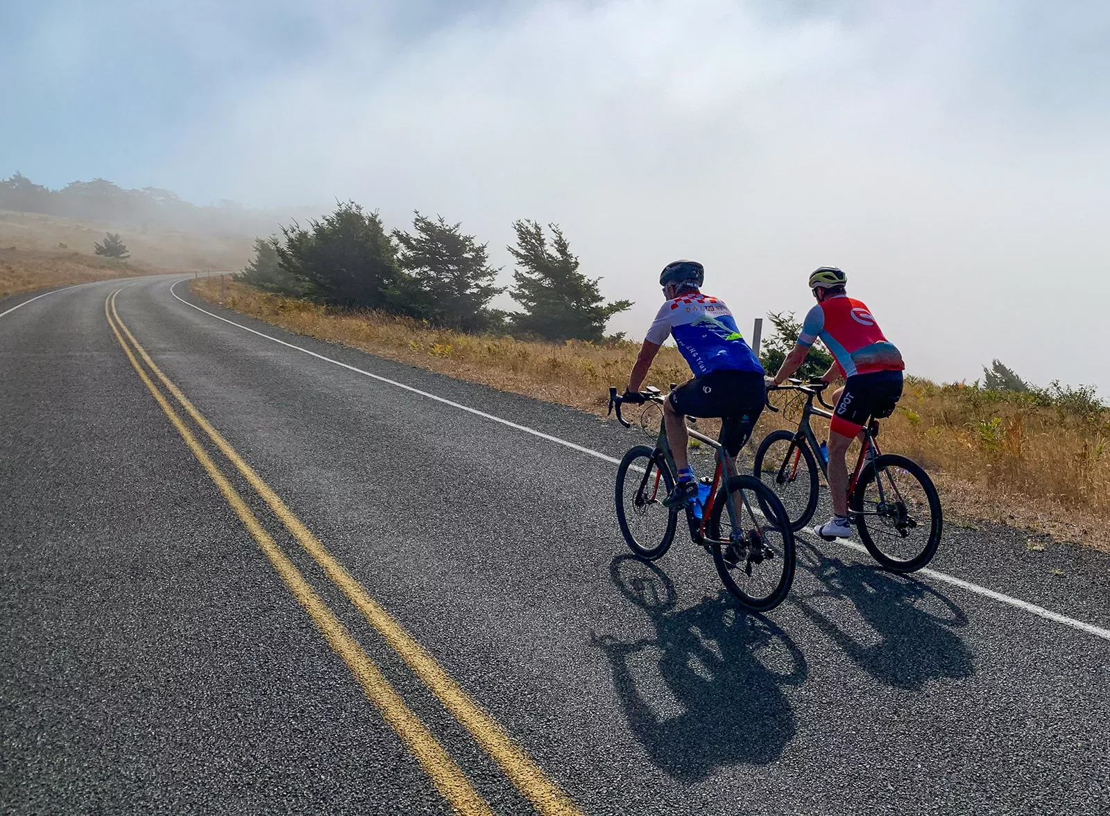 Two guests cycling up foggy road.