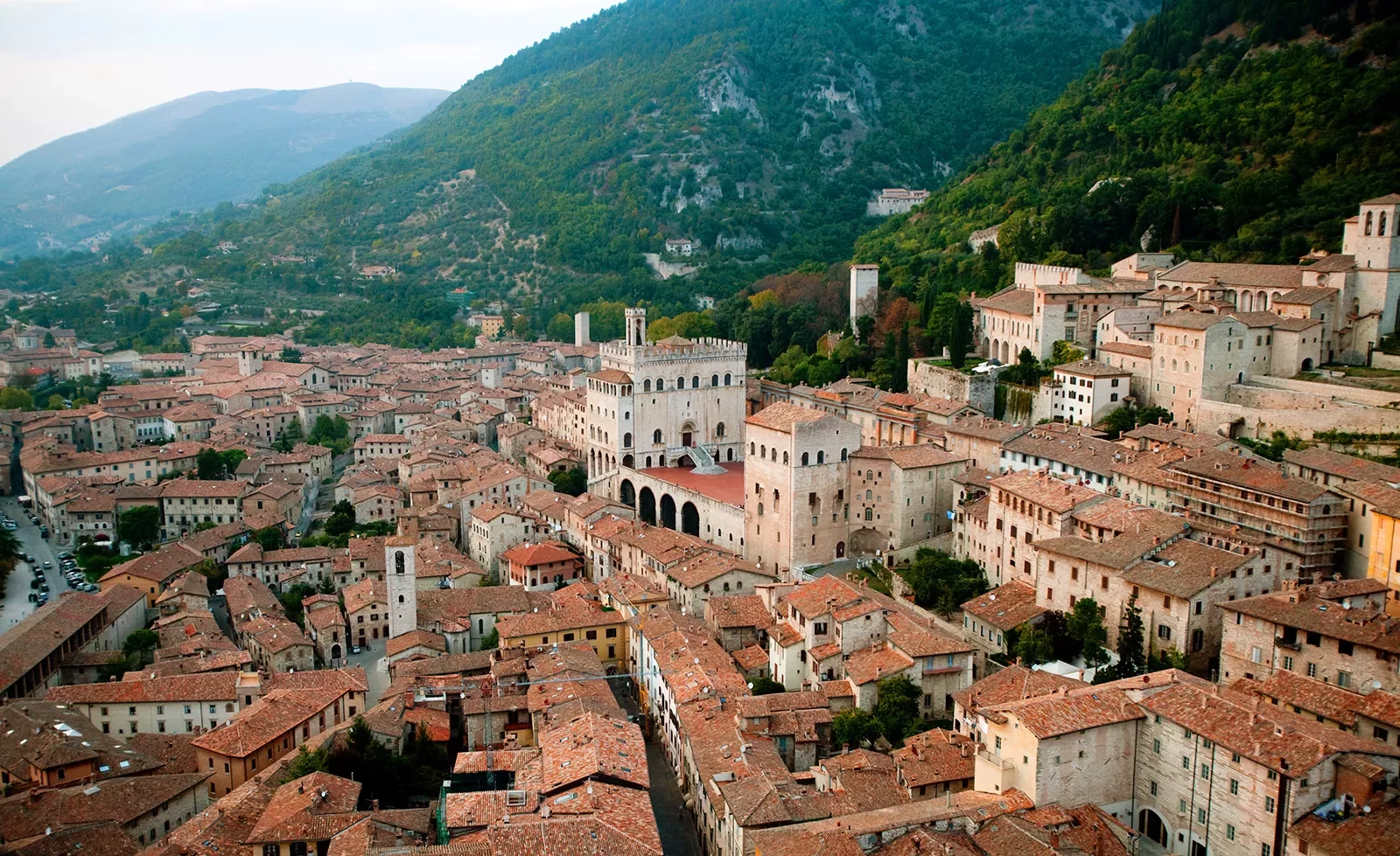 Wide shot of Italian town in valley, terracotta roofing, sandstone brick.
