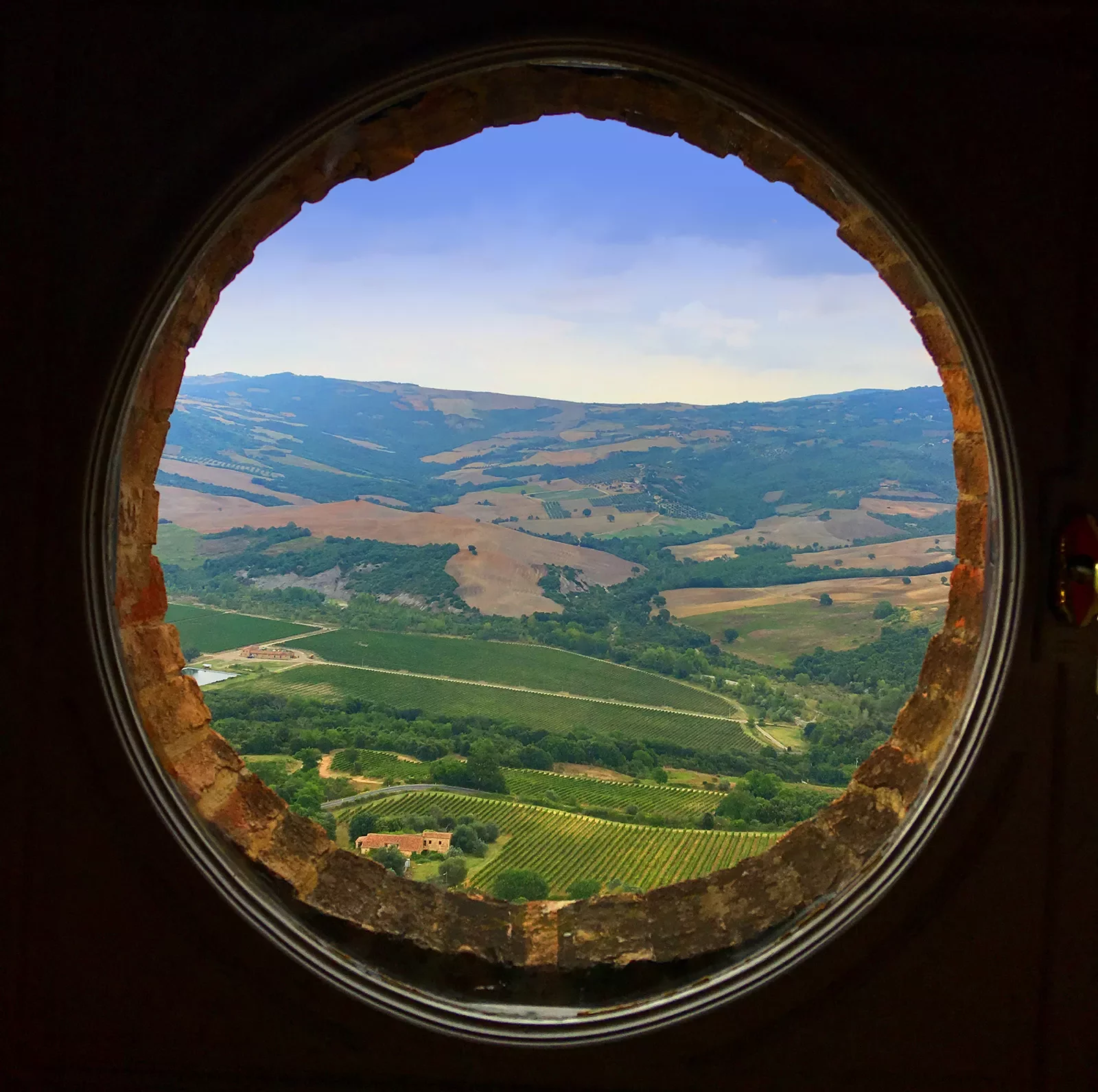 Circular window overlooking Italian countryside.