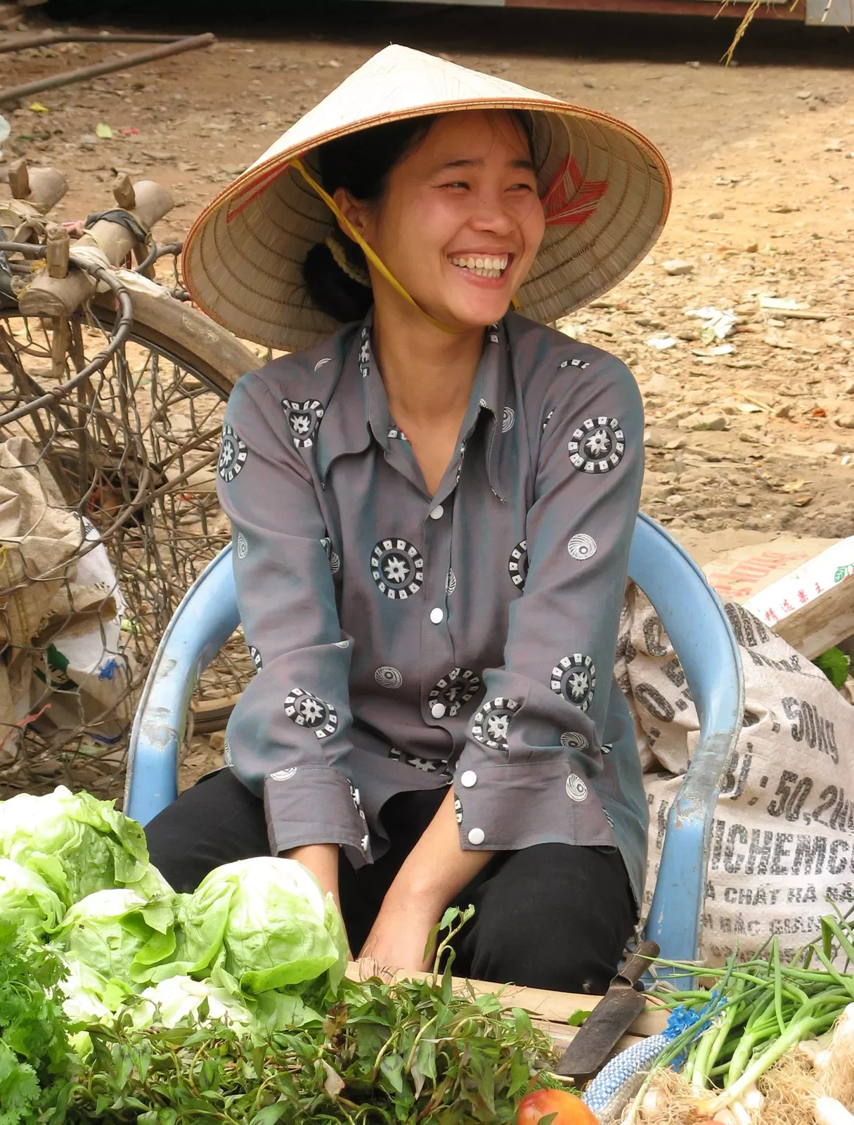 Local smiling in front of vegetable stand.