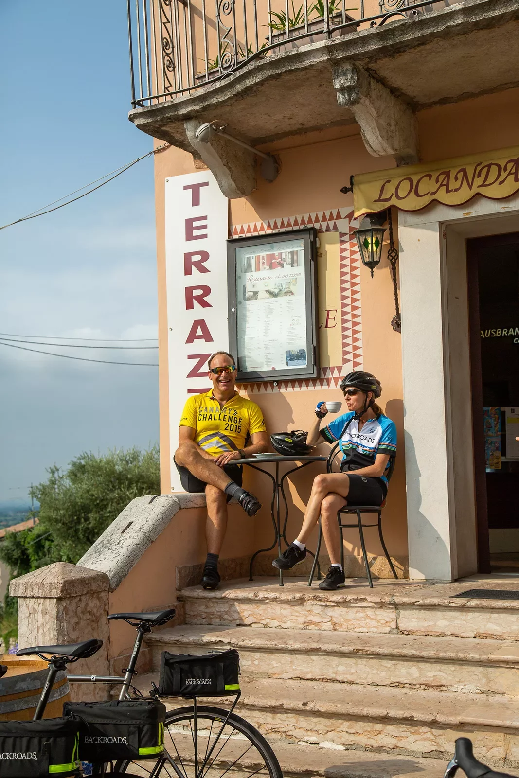 Cyclists enjoying coffees on front steps of a cafe