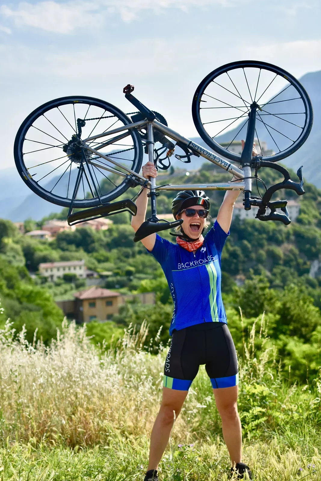 Cyclist holding bike overhead at the top of a hill