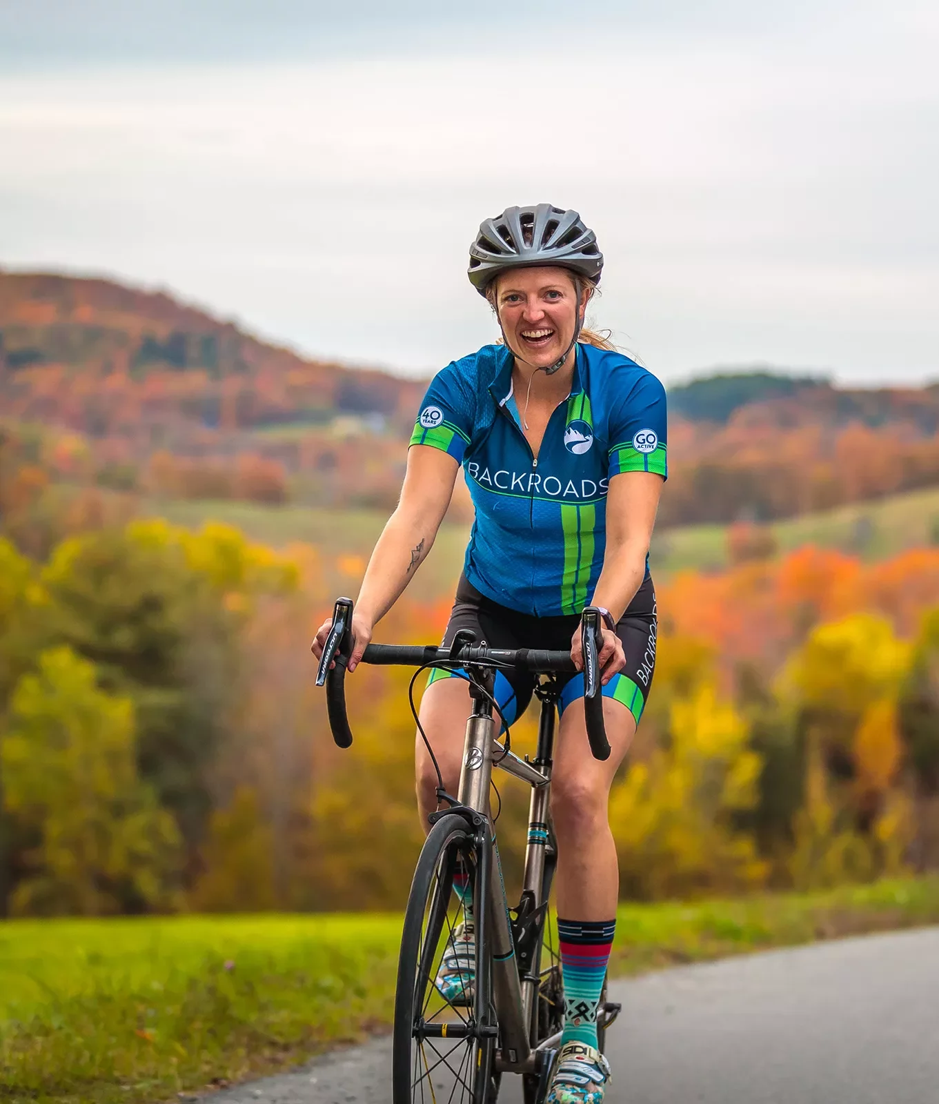 Guest cycling, smiling at camera, trees behind her.