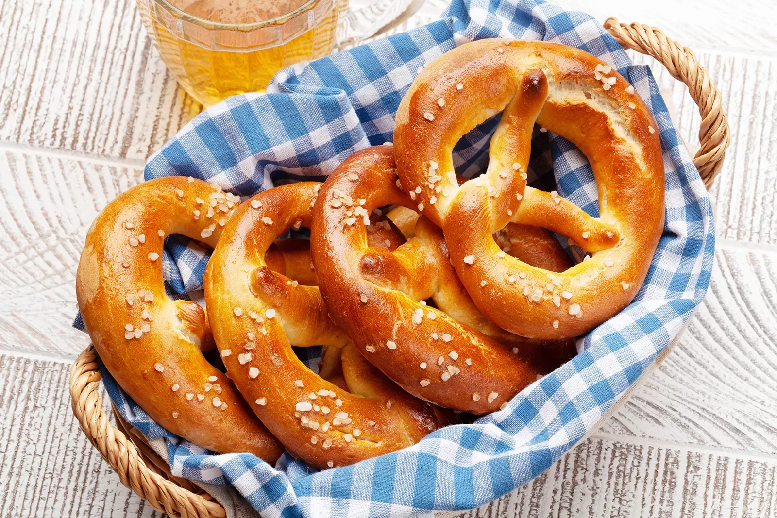 Lager beer mug and fresh baked homemade pretzel with sea salt on wooden table. Classic beer snack