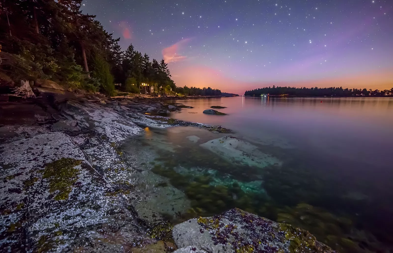 Wide shot of lake at sunset, large stars twinkling in the night sky.