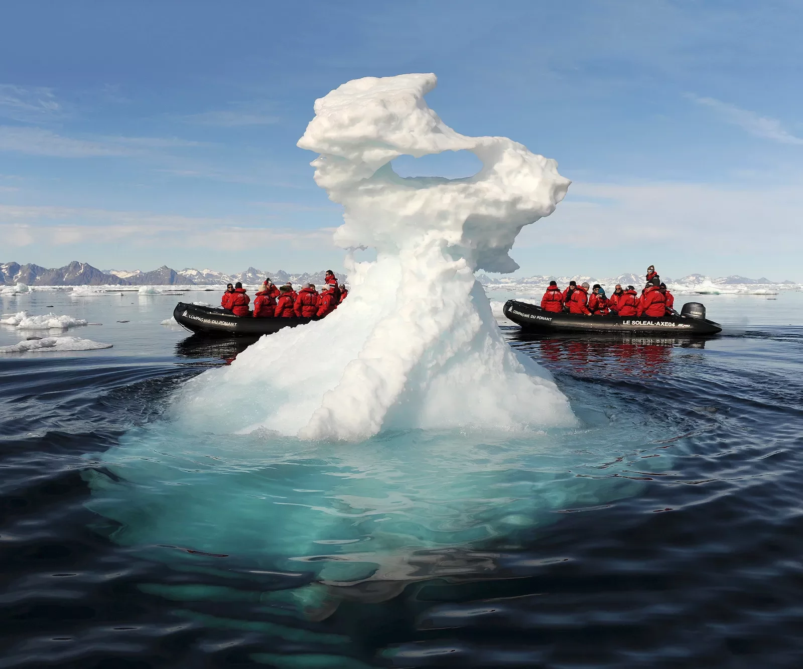 Riding in a zodiac boat past a large iceberg