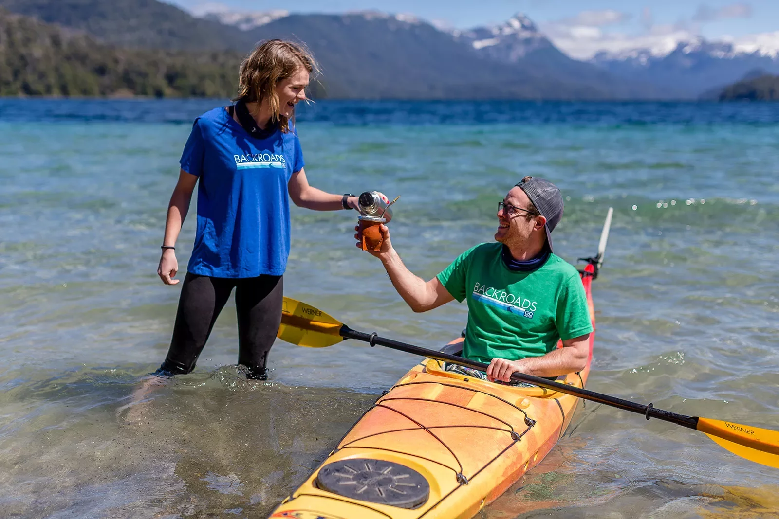 Guest in kayak, leader pouring water in their yerba mate infuser.