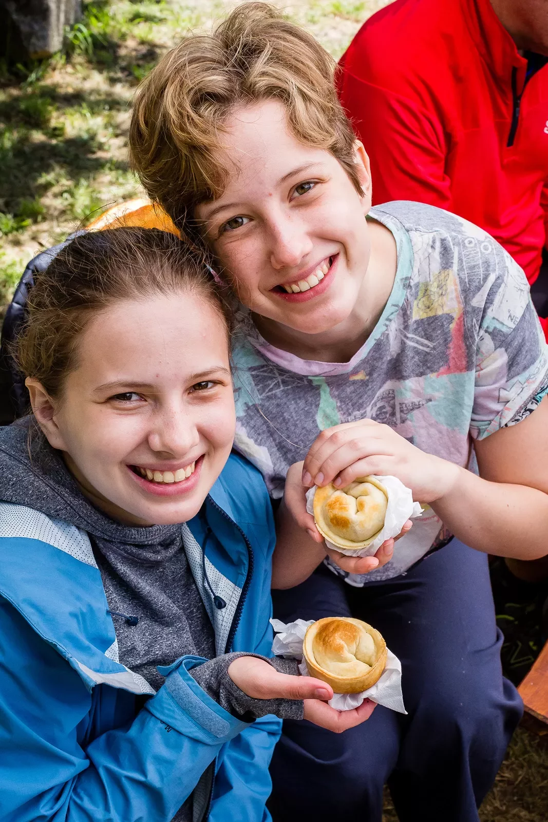 Two young guests smiling at camera, pastries in hand.