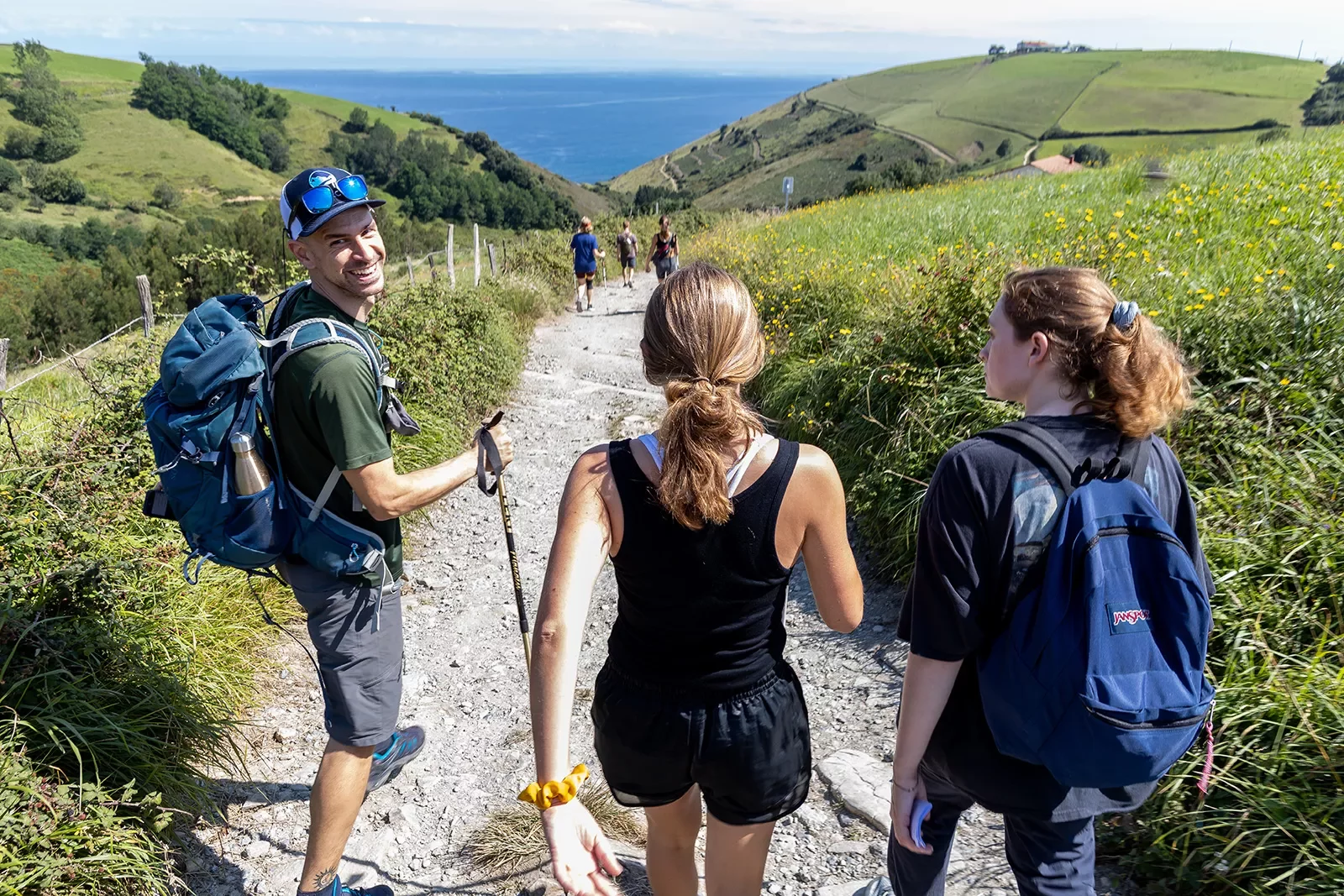 Group of guests walking towards French coast, large hills on either side.
