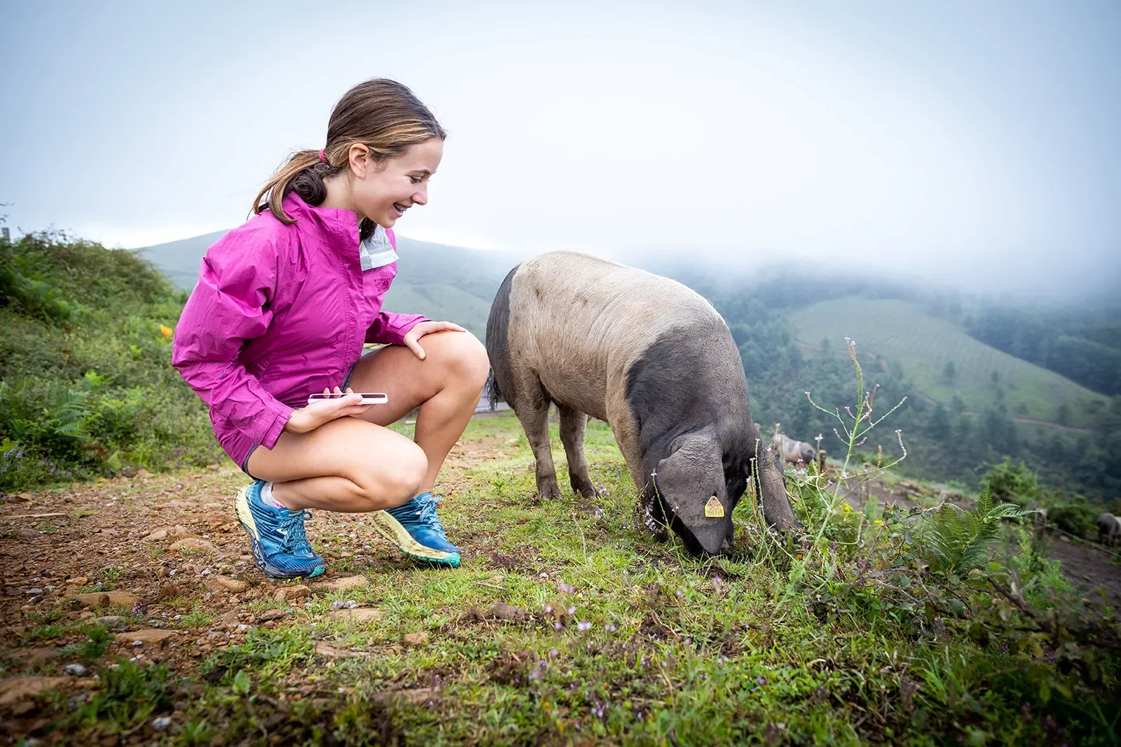 Young guest crouching on hilltop with pig.