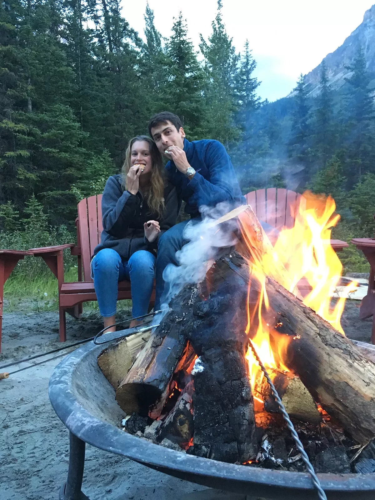 Two guests eating smores around a fire.