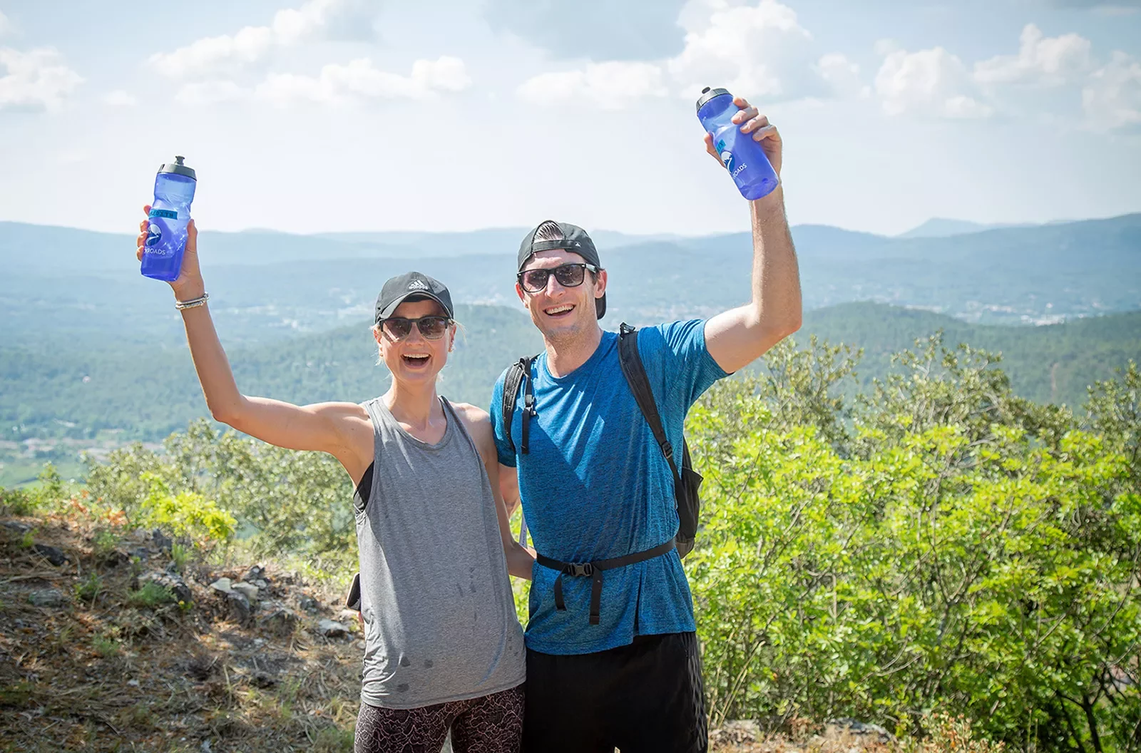 Two guests wearing hiking clothes and holding blue water bottles