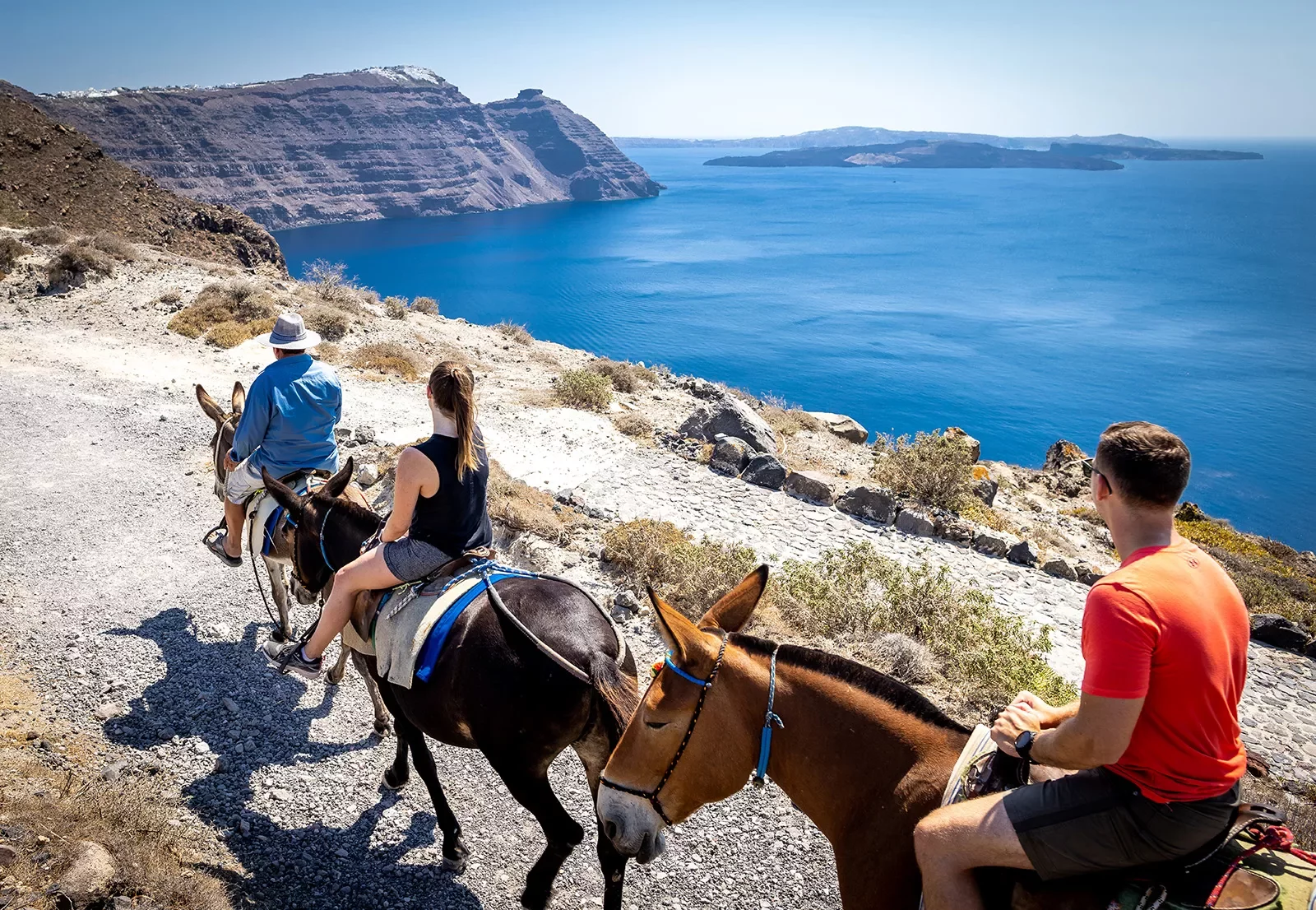 Three guests on horseback, walking along coastline.