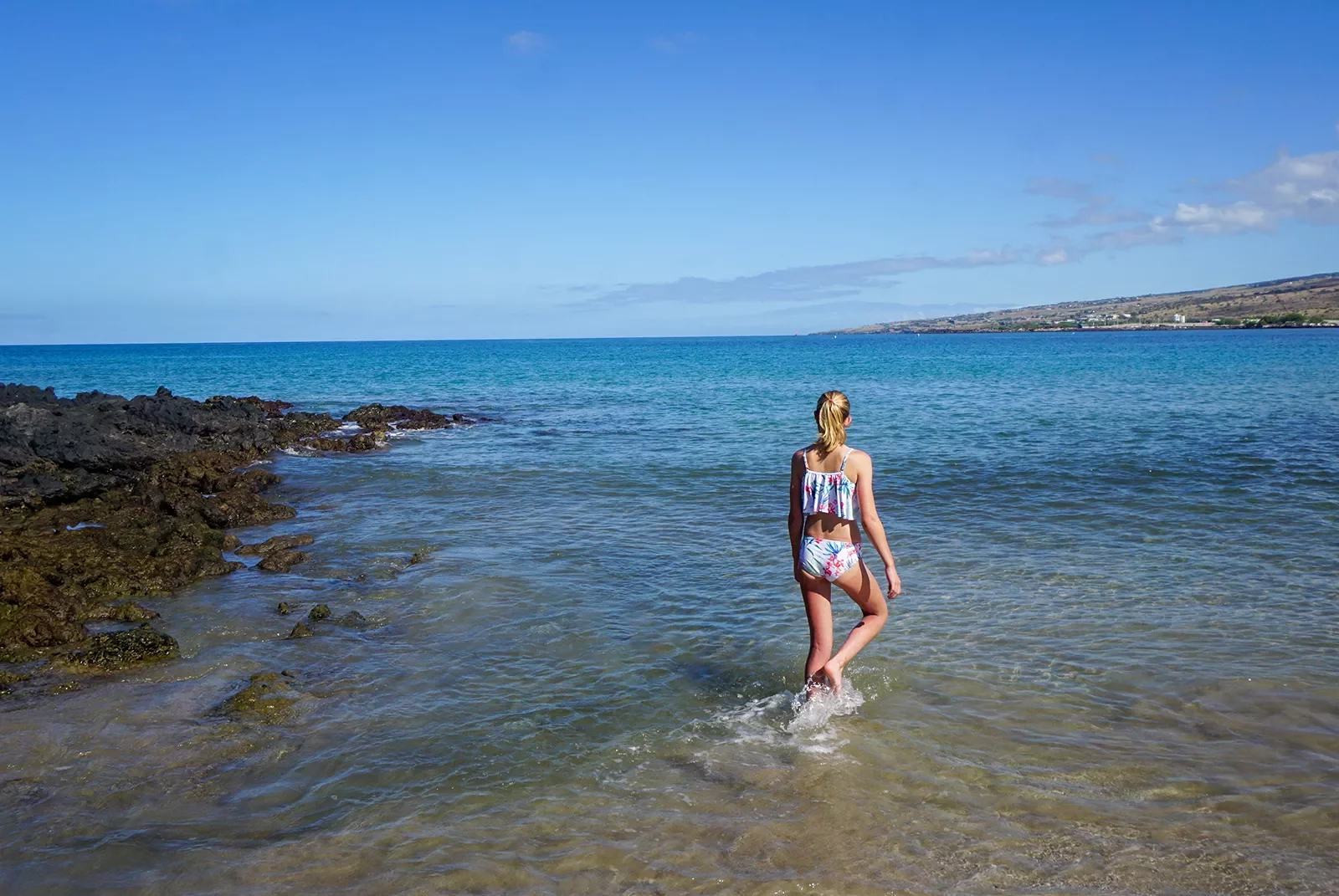 Woman walking in the ocean by the beach in Hawaii