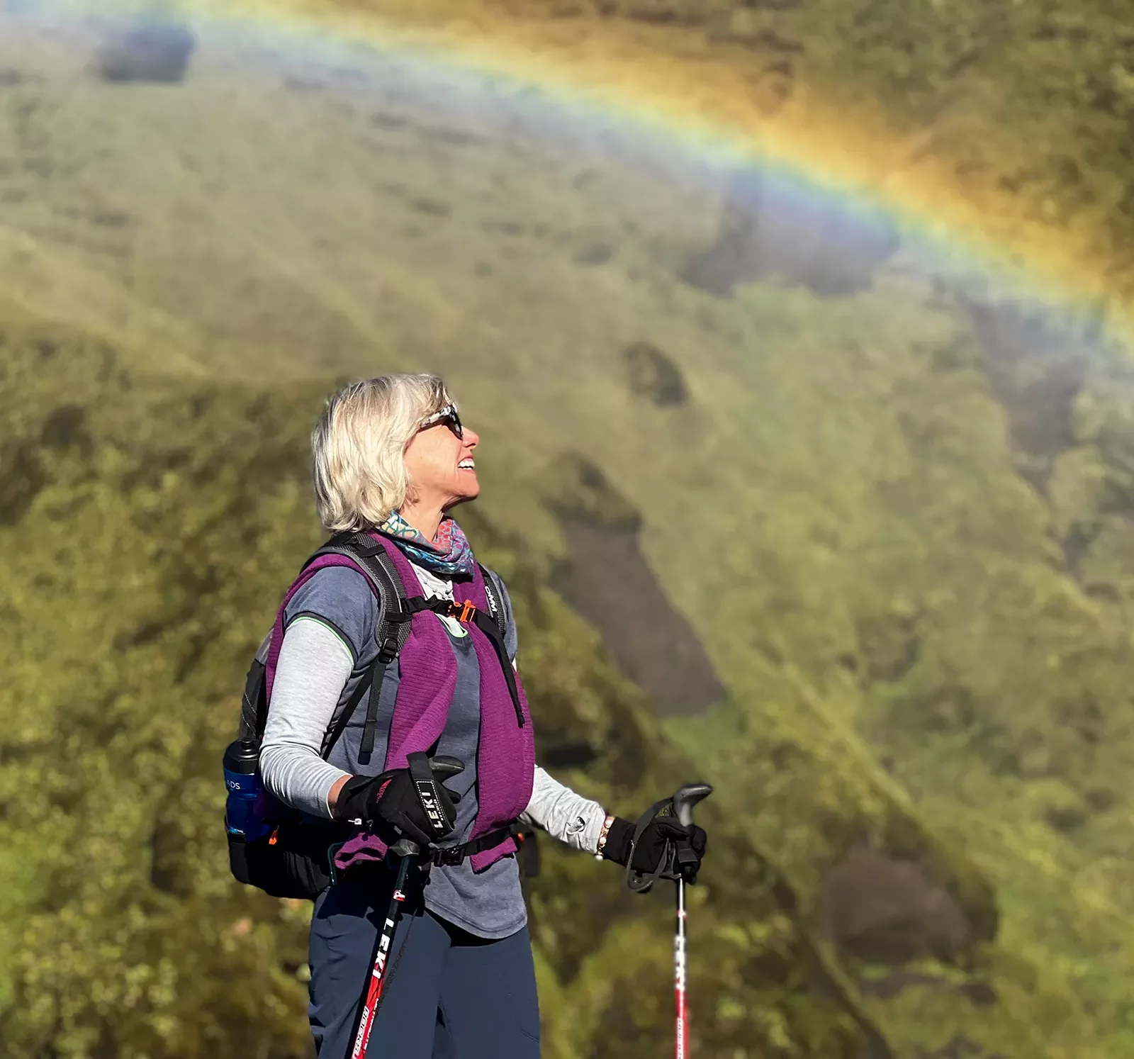 Hiker standing underneath a rainbow.