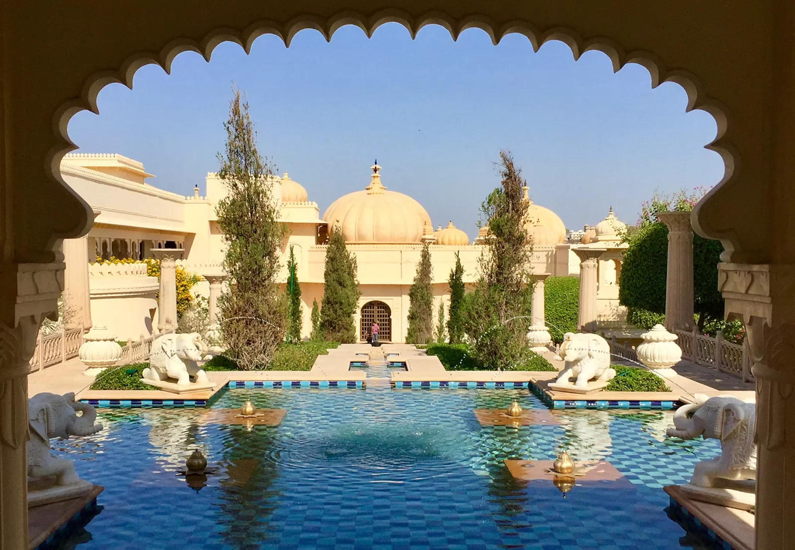 Hotel pool as seen through an ornate arch in India