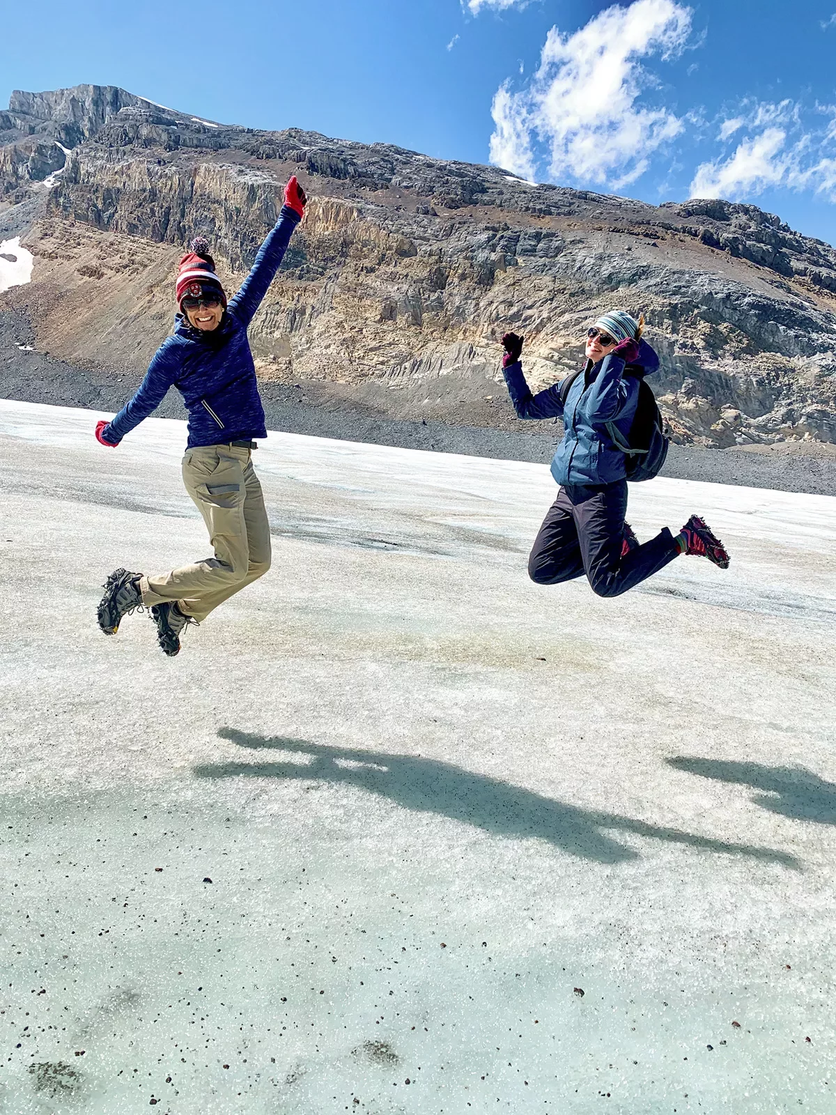Two guests jumping in air on ice shelf.