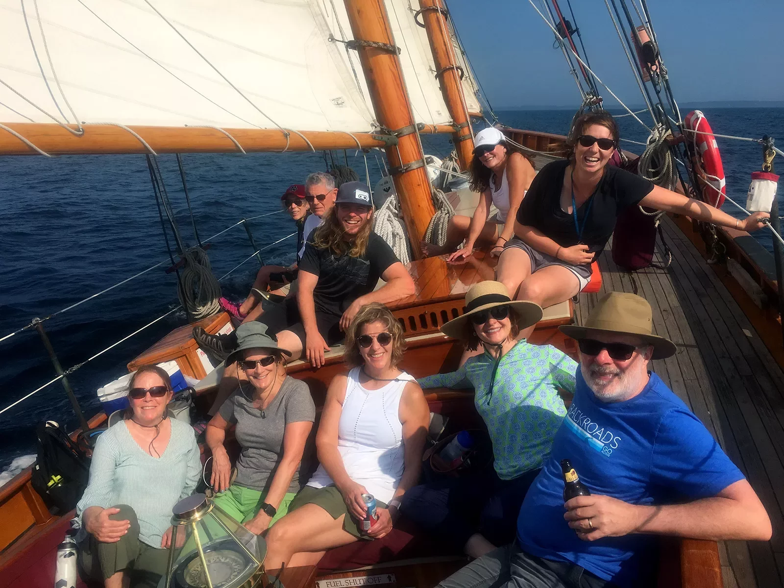 Group of guests on tilting sailboat, all facing camera.