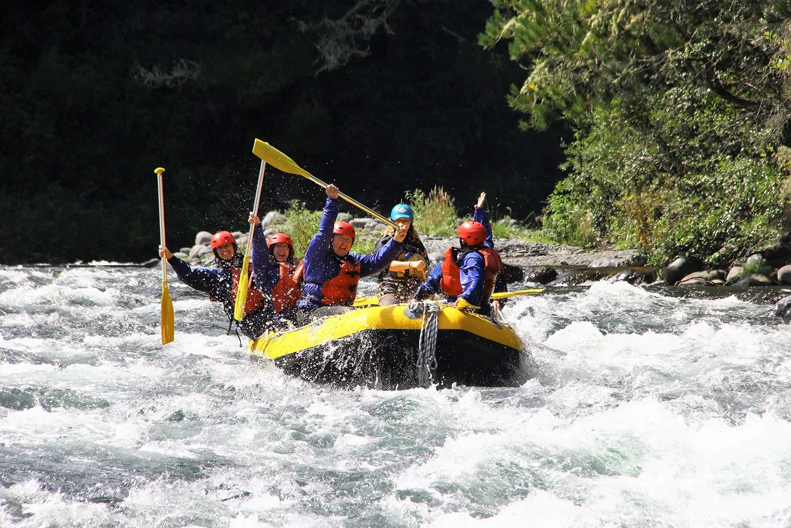 Five guests whit water rafting, all raising oars.