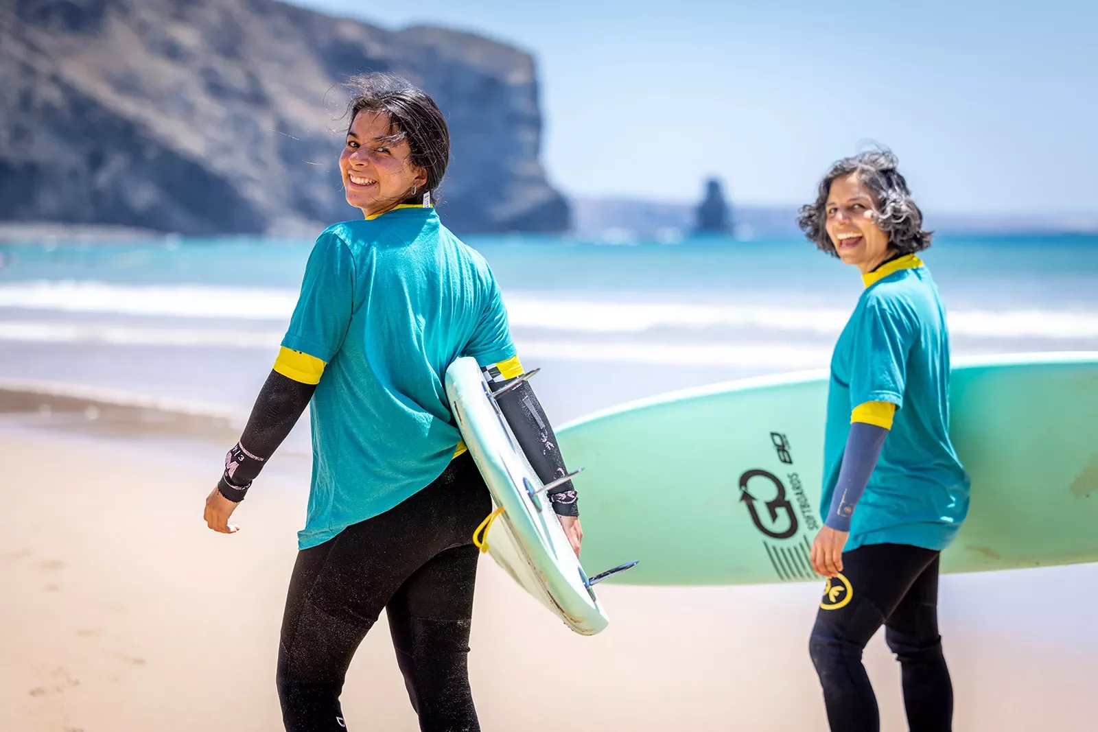 Two women with surfboards walking towards the ocean